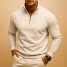 Man wearing a cream quarter-zip pullover sweatshirt and matching sweatpants
